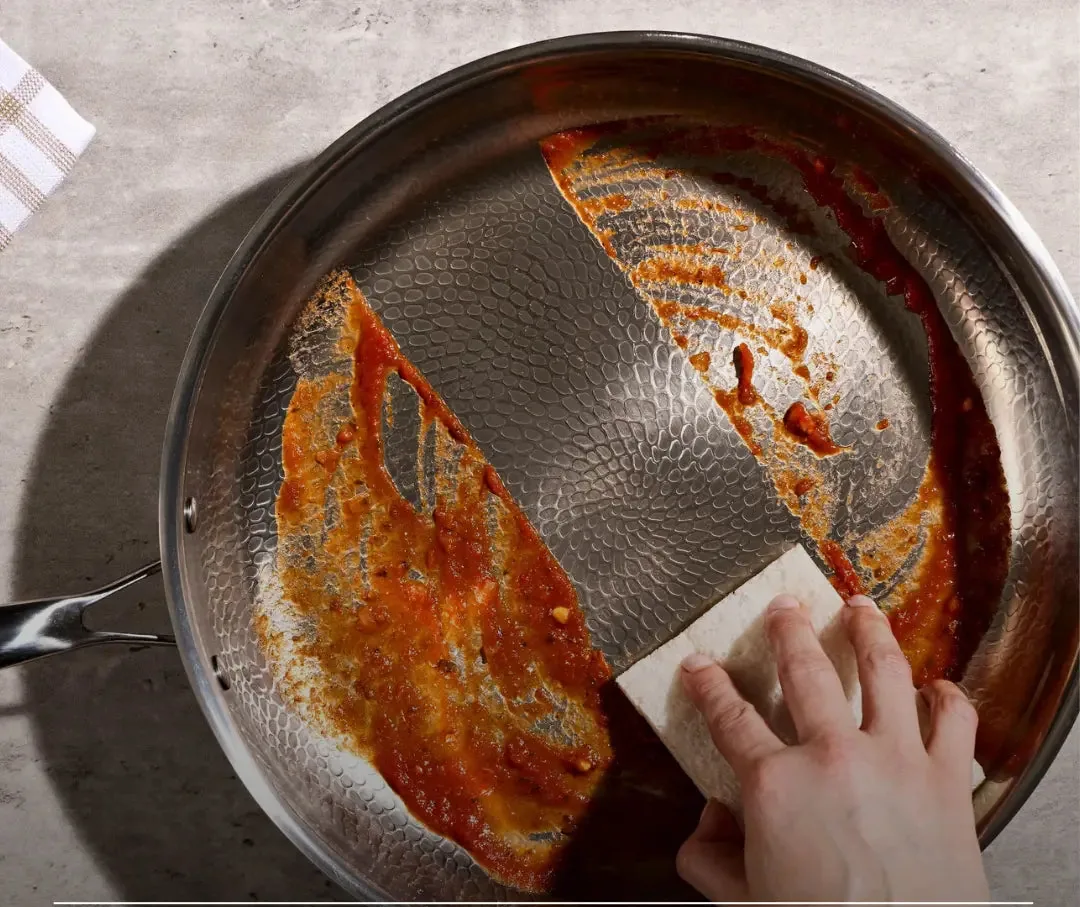 Scrubbing cooked-on sauce off the hammered surface of a Siraat titanium pan